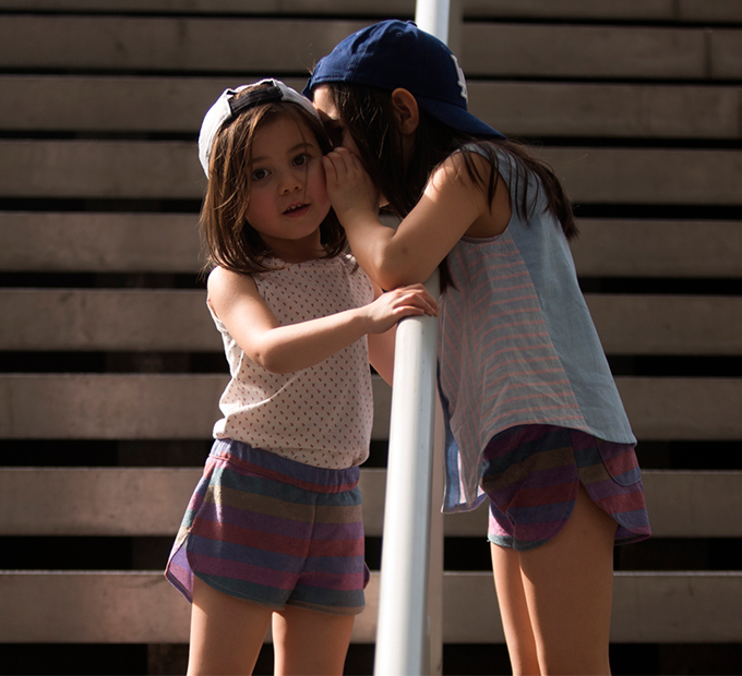 Deux fillettes se chuchotant un secret, short à rayures.