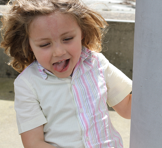 Enfant tirant la langue, chemise à rayures colorées.
