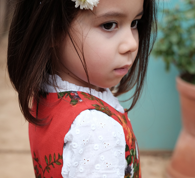 Fillette avec fleur dans les cheveux, tenue rouge et blanche.