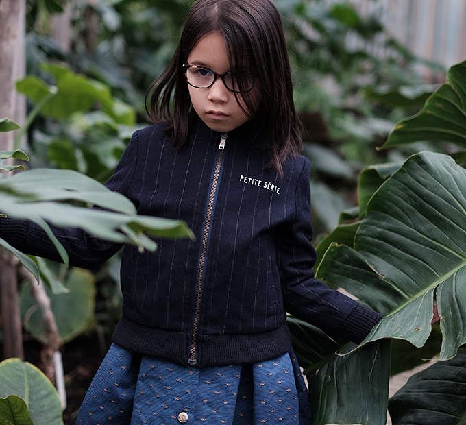 Fillette à lunettes en veste zippée marine Petite Série, végétation.